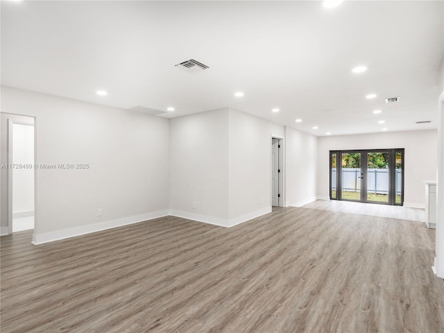 spare room featuring french doors and light hardwood / wood-style flooring