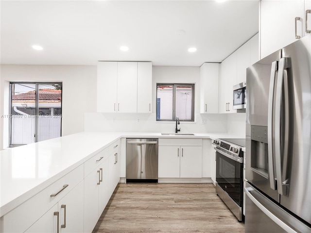 kitchen with white cabinetry, appliances with stainless steel finishes, sink, and light wood-type flooring