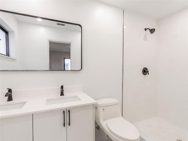 bathroom featuring vanity, toilet, and tiled shower