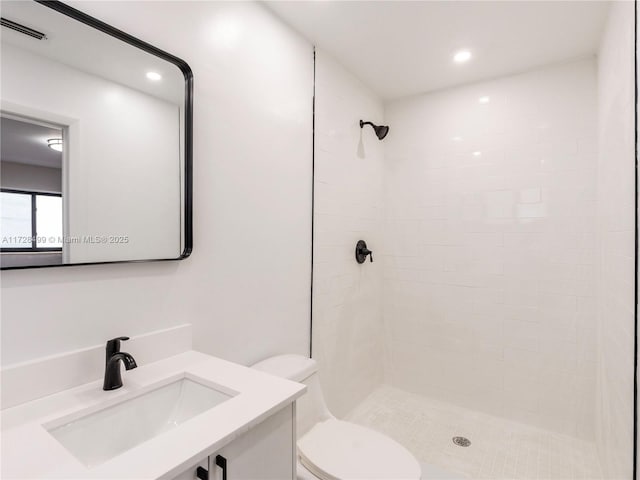 bathroom with vanity, toilet, and tiled shower