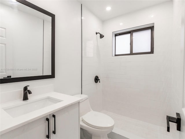 bathroom featuring vanity, a tile shower, and toilet