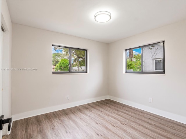 spare room featuring a healthy amount of sunlight and light hardwood / wood-style flooring