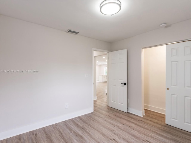 unfurnished bedroom with light wood-type flooring and a closet