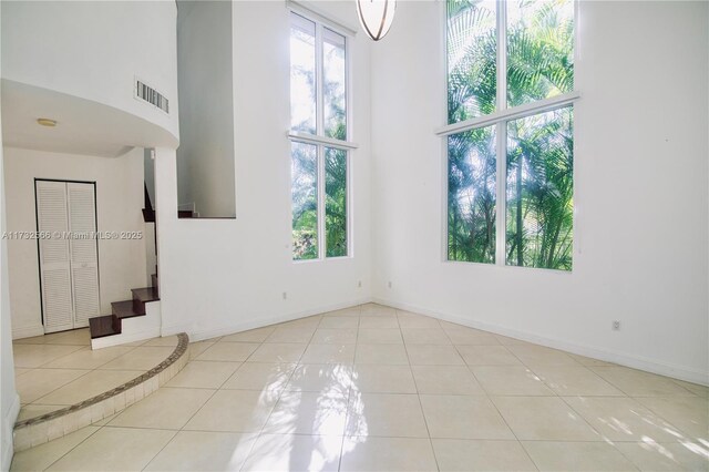 tiled empty room featuring a high ceiling