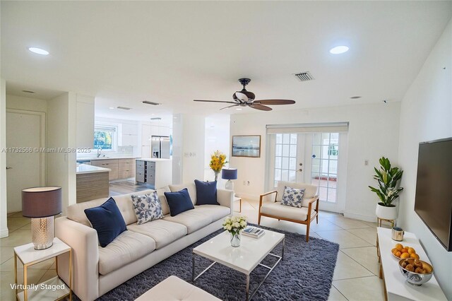 tiled living room with french doors, ceiling fan, sink, and a wealth of natural light