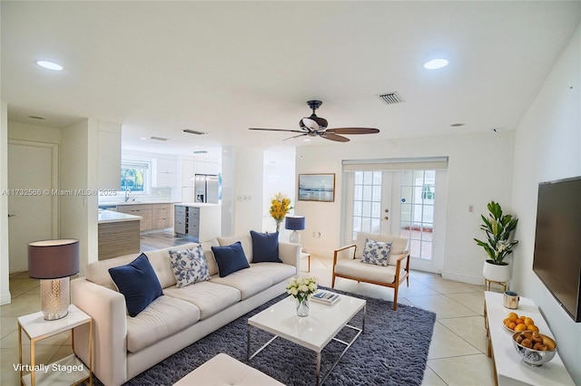 tiled living room with sink, ceiling fan, and french doors