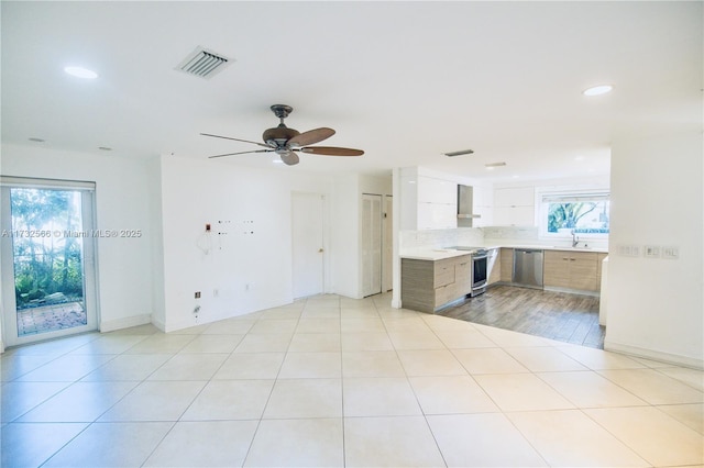 kitchen with plenty of natural light, stainless steel appliances, light tile patterned floors, and wall chimney range hood