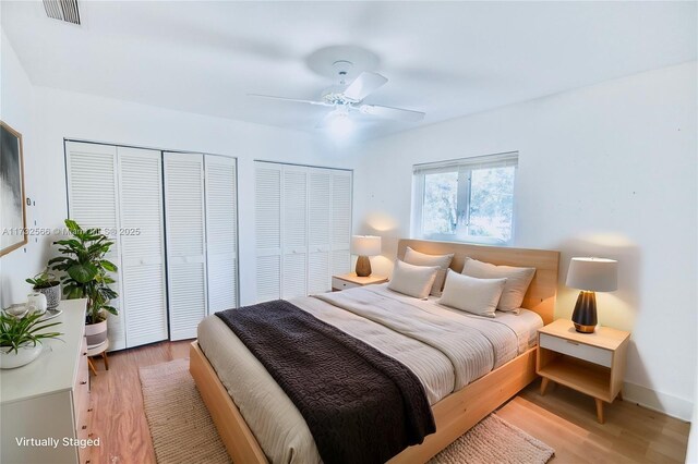 bedroom featuring multiple closets, ceiling fan, and light hardwood / wood-style floors