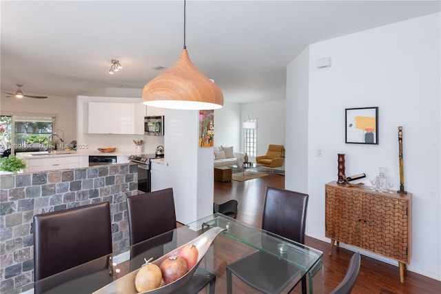 dining area with ceiling fan, dark hardwood / wood-style floors, and sink