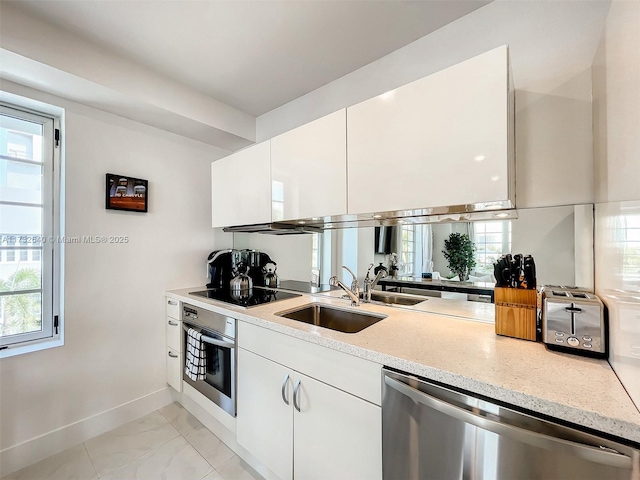 kitchen featuring stainless steel appliances, light stone countertops, sink, and white cabinets