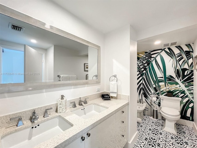 bathroom featuring a bidet, vanity, tile patterned floors, and toilet