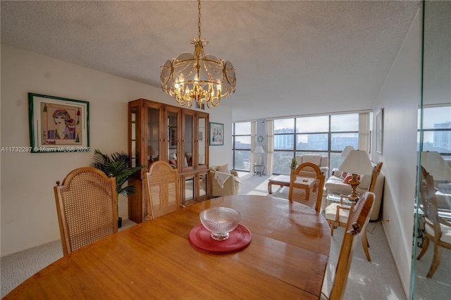 dining room featuring an inviting chandelier, a wall of windows, carpet, and a textured ceiling