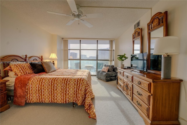 bedroom with ceiling fan, a wall of windows, light colored carpet, and a textured ceiling