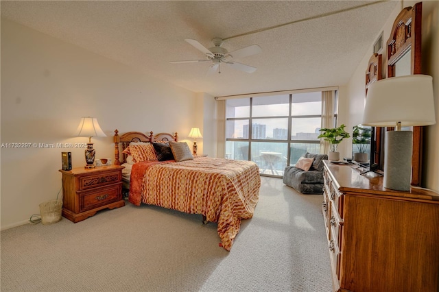 bedroom featuring ceiling fan, expansive windows, a textured ceiling, and carpet flooring