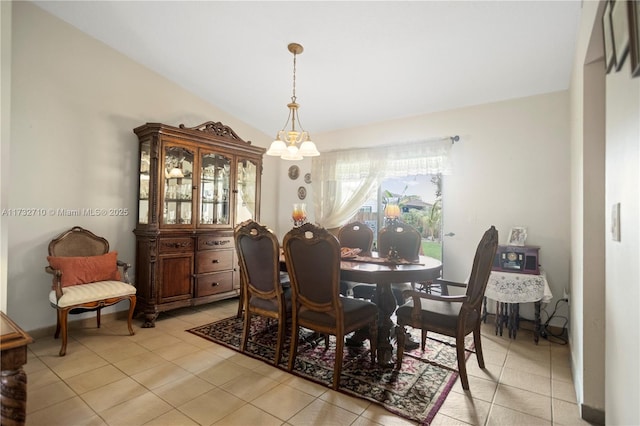 dining area with light tile patterned floors, a notable chandelier, and vaulted ceiling