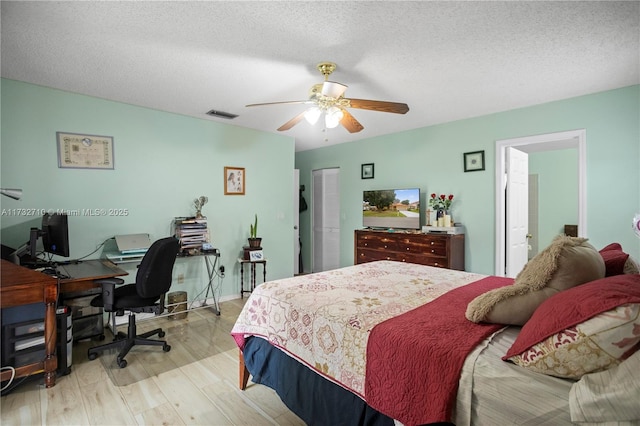 bedroom with ceiling fan, a closet, a textured ceiling, and light wood-type flooring