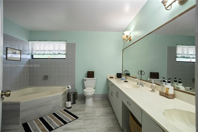 bathroom with vanity, tile patterned flooring, a relaxing tiled tub, and toilet