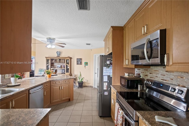 kitchen with tasteful backsplash, sink, light tile patterned floors, stainless steel appliances, and a textured ceiling