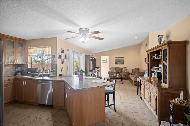 kitchen featuring sink, stainless steel dishwasher, a kitchen breakfast bar, and light tile patterned floors