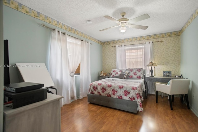 bedroom with ceiling fan, hardwood / wood-style floors, and a textured ceiling