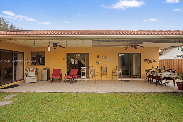 back of house with ceiling fan, a patio area, and a lawn