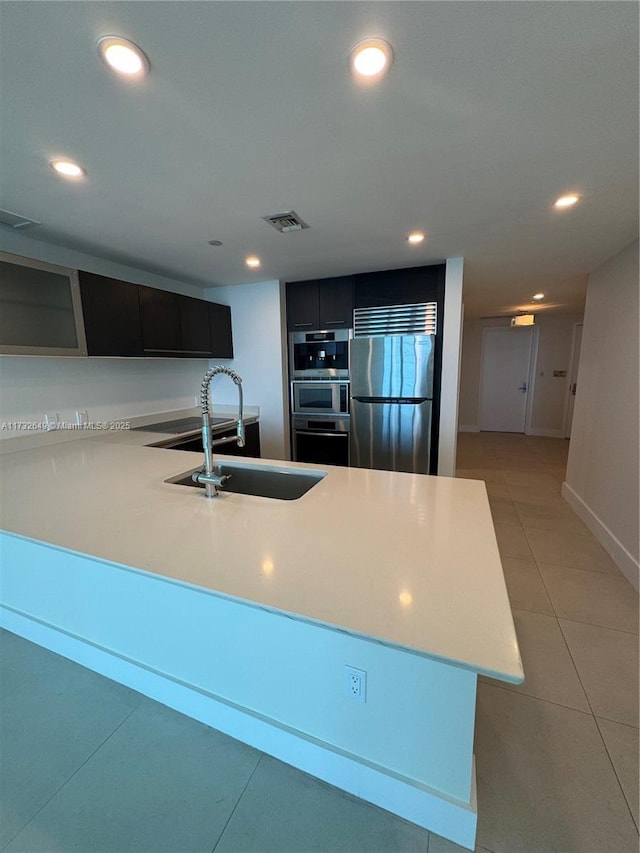 kitchen with stainless steel appliances, sink, and light tile patterned floors