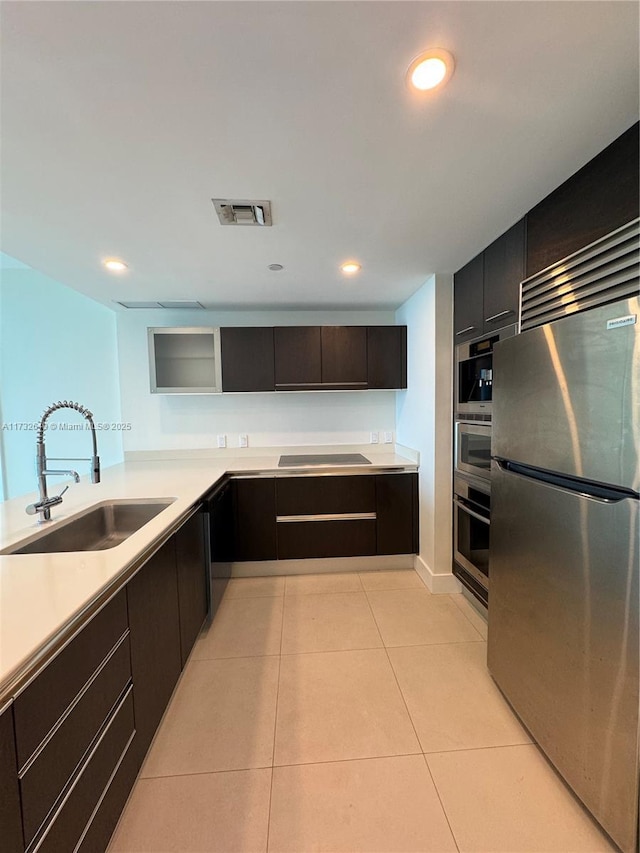 kitchen with light tile patterned flooring, sink, black electric stovetop, and stainless steel refrigerator