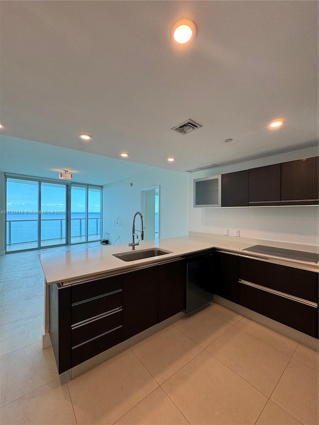 kitchen featuring sink, black electric stovetop, light tile patterned floors, and kitchen peninsula