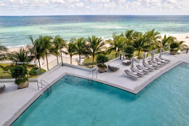 view of pool featuring a water view, a beach view, and a patio