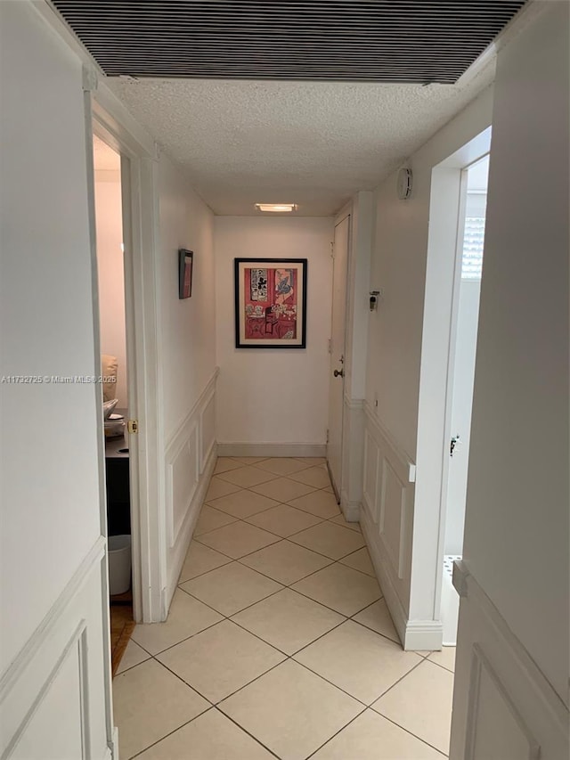 hallway featuring light tile patterned floors and a textured ceiling