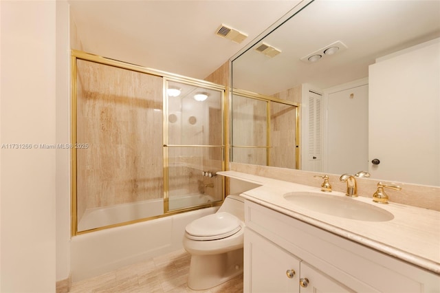 full bathroom with tile patterned flooring, bath / shower combo with glass door, vanity, and toilet