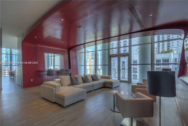 living room featuring wood-type flooring, expansive windows, and french doors