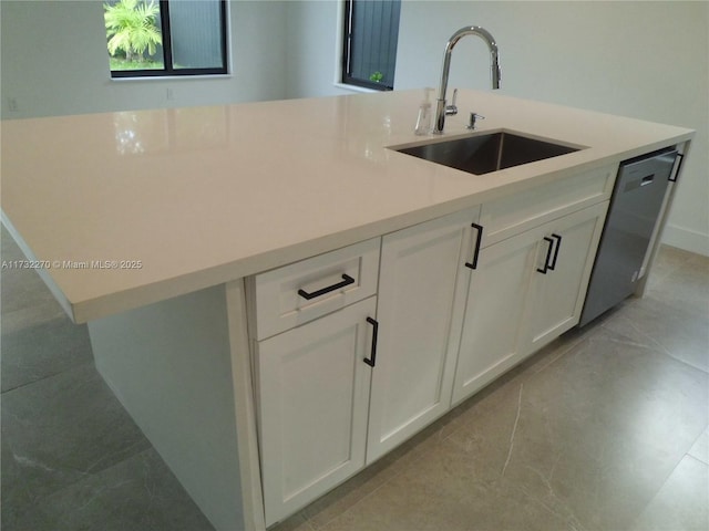 kitchen featuring stainless steel dishwasher, sink, and white cabinets