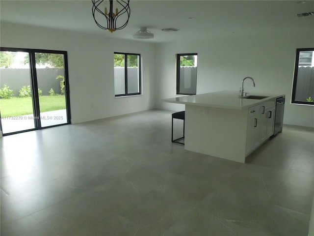 kitchen featuring sink, dishwasher, pendant lighting, a kitchen island with sink, and white cabinets