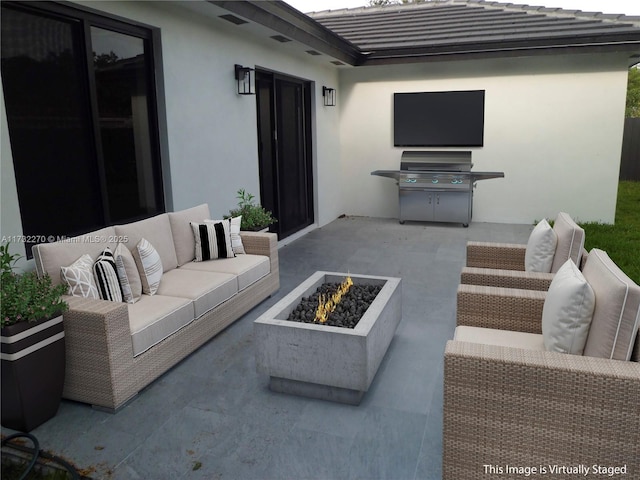 view of patio with grilling area and an outdoor living space with a fire pit