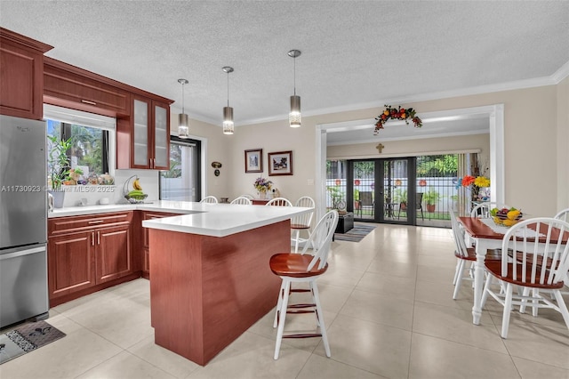 kitchen with decorative light fixtures, stainless steel fridge, french doors, and plenty of natural light