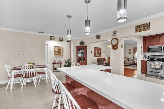 kitchen with crown molding, appliances with stainless steel finishes, light tile patterned floors, and decorative light fixtures