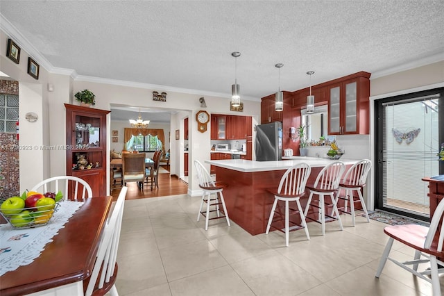 kitchen featuring crown molding, pendant lighting, stainless steel fridge, and kitchen peninsula