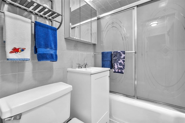 full bathroom featuring enclosed tub / shower combo, tile walls, vanity, and toilet