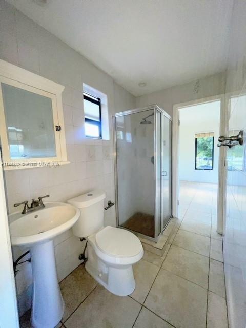 bathroom featuring walk in shower, tile walls, tile patterned floors, and toilet