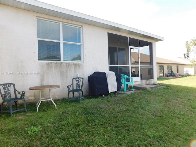 back of house featuring a sunroom and a lawn