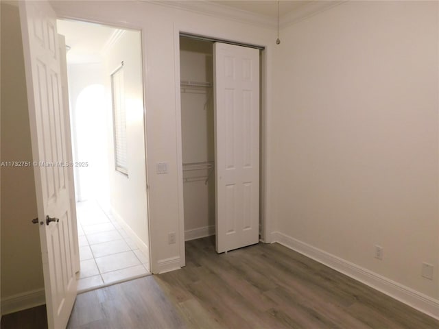 unfurnished bedroom with crown molding, hardwood / wood-style floors, and a closet