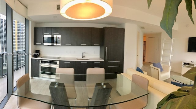 kitchen featuring light tile patterned flooring, sink, stainless steel counters, appliances with stainless steel finishes, and a wall of windows