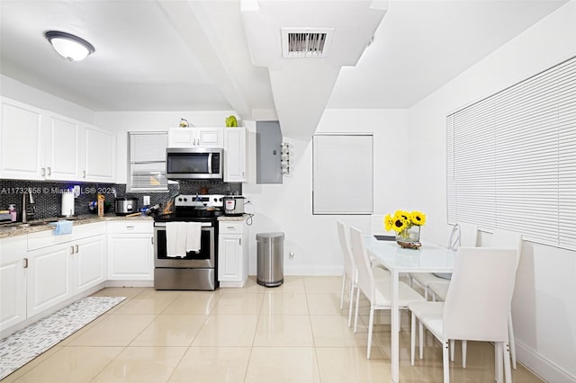 kitchen with sink, light tile patterned floors, stainless steel appliances, white cabinets, and decorative backsplash