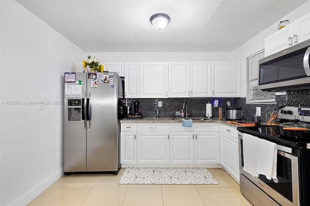 kitchen featuring sink, white cabinetry, stone countertops, appliances with stainless steel finishes, and backsplash