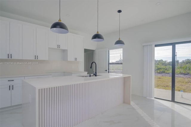 kitchen with an island with sink, a healthy amount of sunlight, sink, and white cabinets