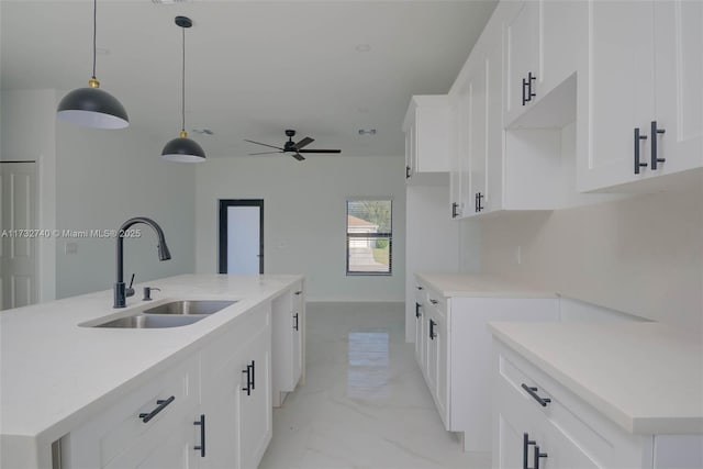 kitchen with pendant lighting, sink, a center island with sink, and white cabinets