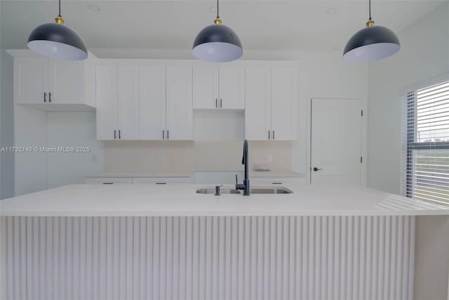 kitchen featuring sink, hanging light fixtures, and an island with sink