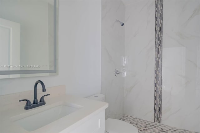 bathroom featuring tiled shower, vanity, and toilet