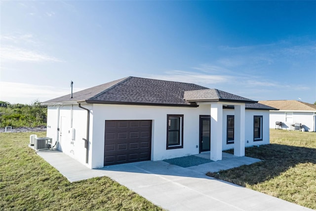 view of front of home with a garage, central AC unit, and a front lawn